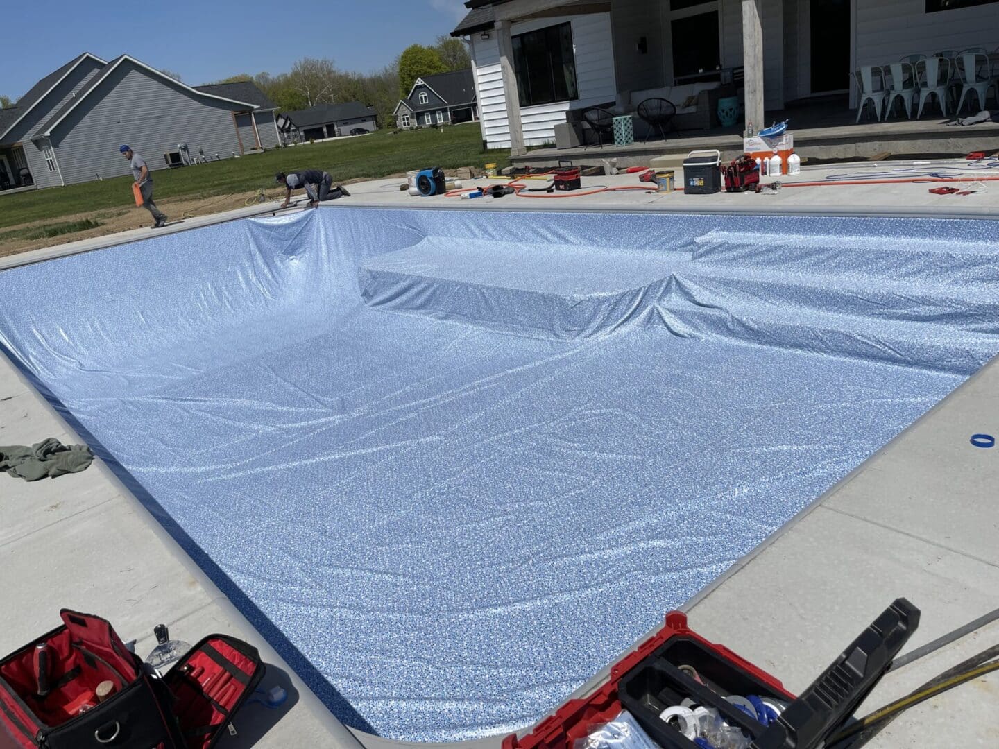 A pool cover being installed in the backyard.