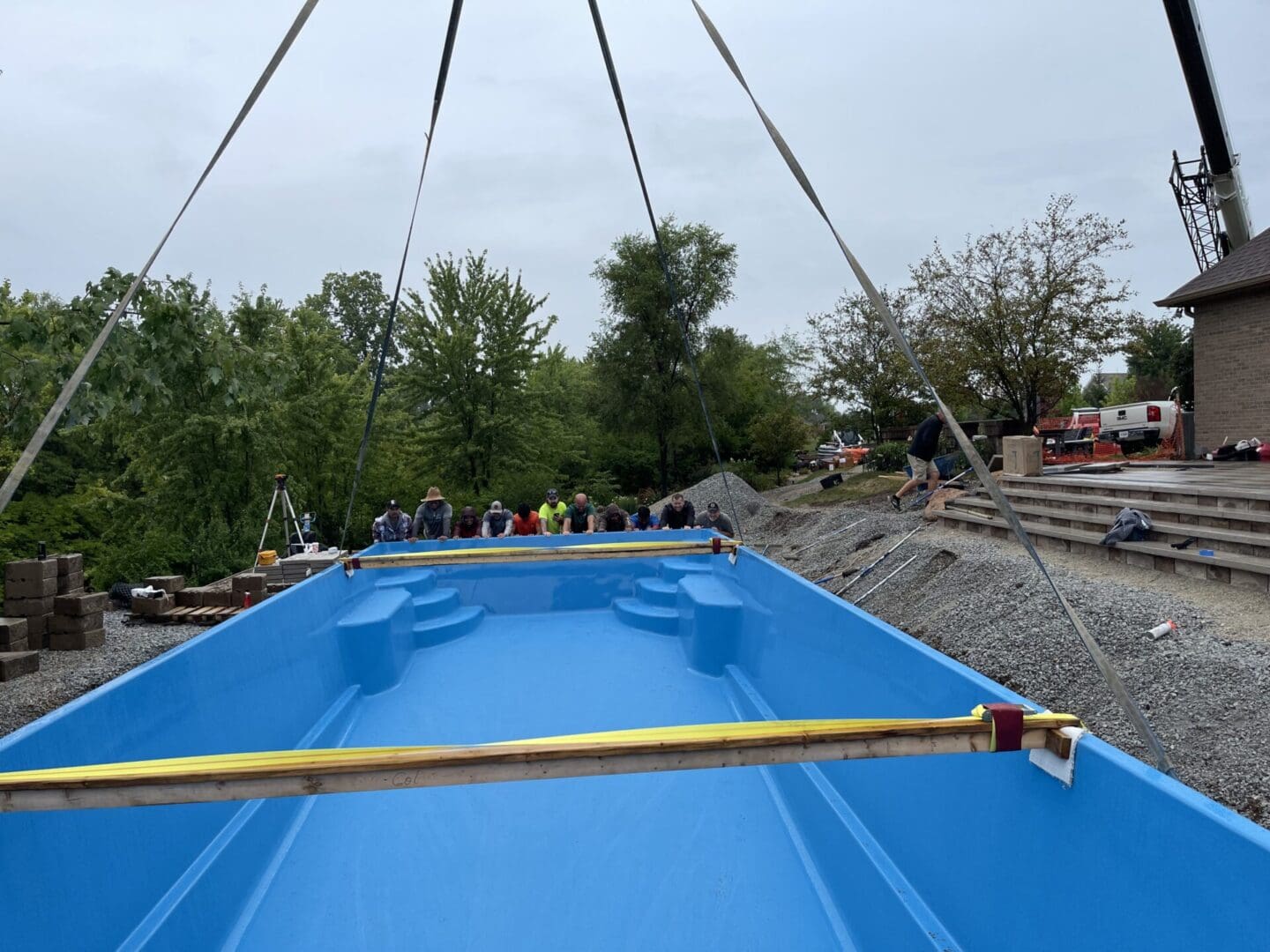 A blue boat is being lowered into the water.