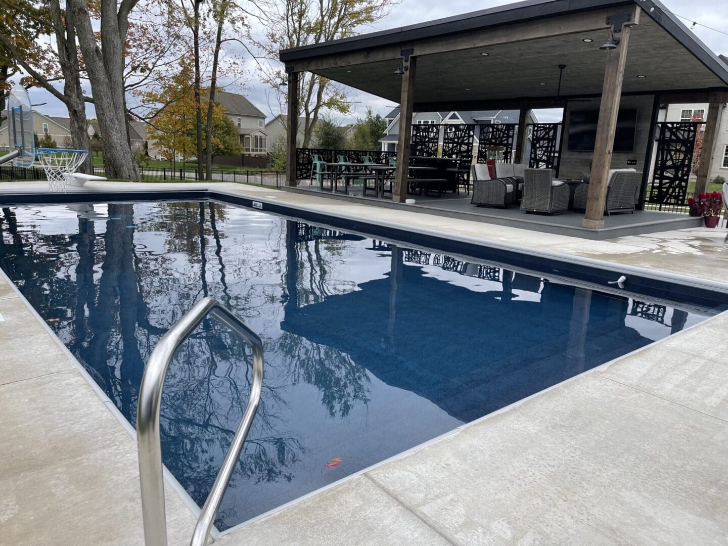 A pool with a bench and table in the background.